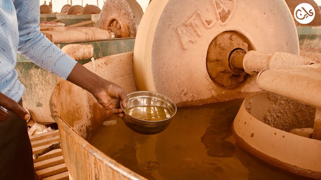 Un ouvrier soudanais verse une solution chimique dans un bassin de traitement du minerai d'or, à côté de grandes meules de broyage, sur un site d'orpaillage artisanal de l'État du Nil, au Soudan.