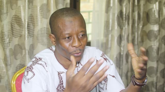 Jean-Claude Katende, président de l'ASADHO, assis et s'exprimant en gesticulant des deux mains lors d'un entretien à Kinshasa