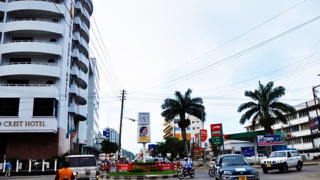 Rue commerçante du centre-ville de Mwanza, en Tanzanie, bordée d'immeubles et de boutiques, avec des piétons et des véhicules.