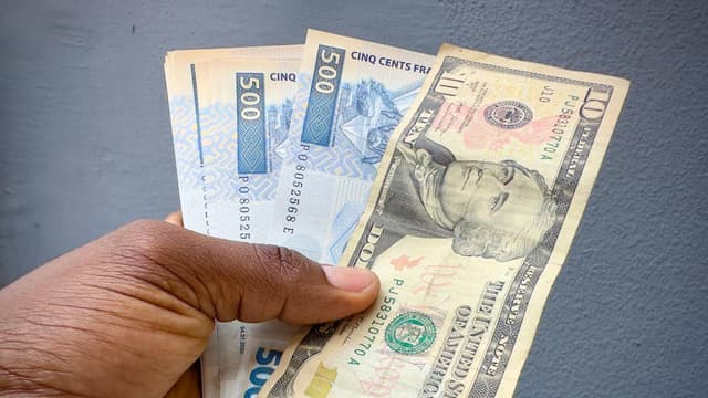 Des billets de francs congolais étalés autour d'un billet de dix dollars américains