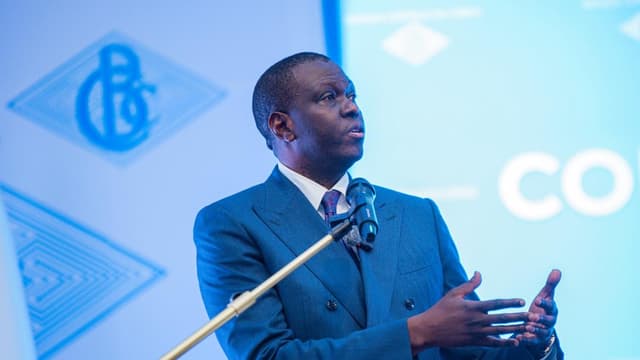 André Wameso, gouverneur de la Banque centrale du Congo, s'exprime debout au pupitre devant un micro lors d'une conférence de presse du Comité de politique monétaire, le logo de la BCC projeté derrière lui