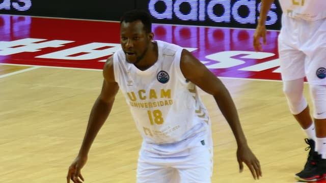 Le basketteur congolais Jordan Sakho, en maillot blanc floqué du numéro 18, bras écartés en position défensive sur un parquet, pendant un match de championnat.