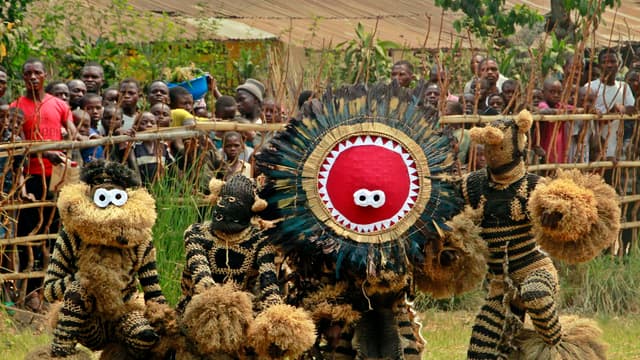 Danseurs pende masqués en costumes de raphia (masques Minganji) au Festival national de Gungu, devant la foule.
