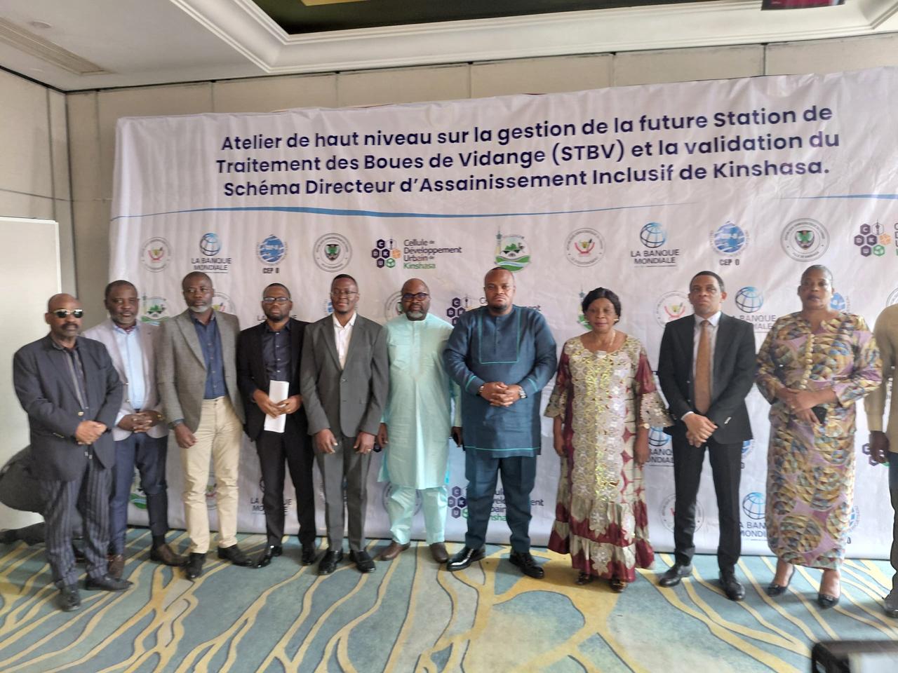 Participants et experts posant devant la banderole de l'atelier de haut niveau sur la future Station de traitement des boues de vidange (STBV) de Kinshasa, dans un hôtel de la capitale congolaise.