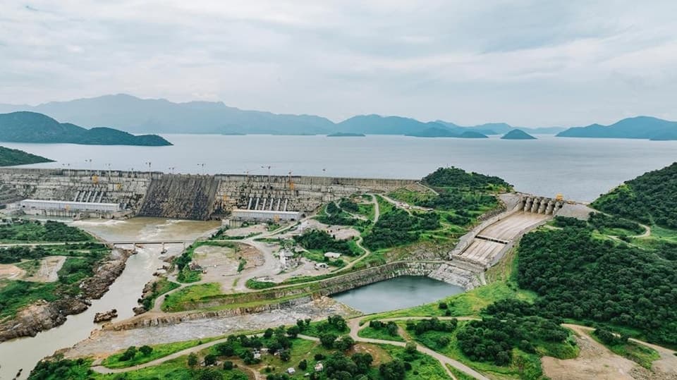 Le mur de béton du Grand barrage de la Renaissance éthiopien retenant les eaux du Nil Bleu, son réservoir rempli, sous un ciel dégagé.