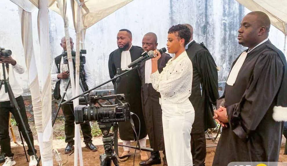 La chanteuse Rebo Tchulo, en chemisier blanc à pois, debout au micro et entourée de ses avocats en robe noire, lors d'une audience du tribunal militaire de garnison de Ngaliema, sous une tente et devant les caméras de la presse.
